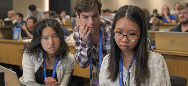 From left to right, Ada and her friends Ethan and Hannah working on a hackathon project around a single laptop.